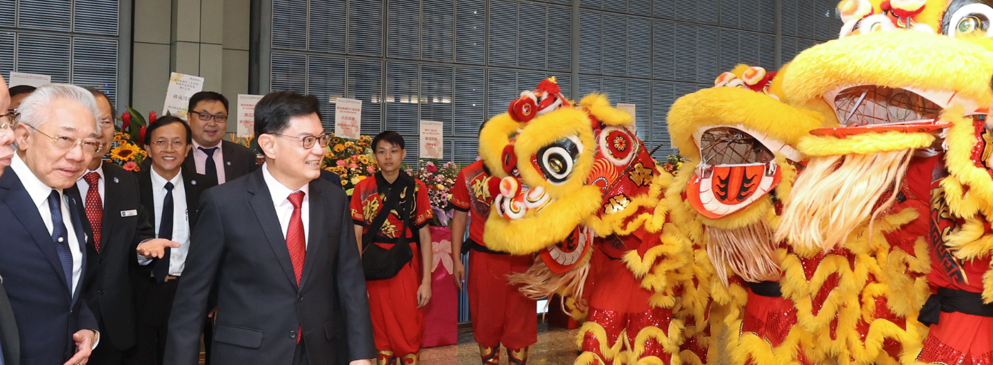 Businessmen stand with performers in red and gold lion costumes.